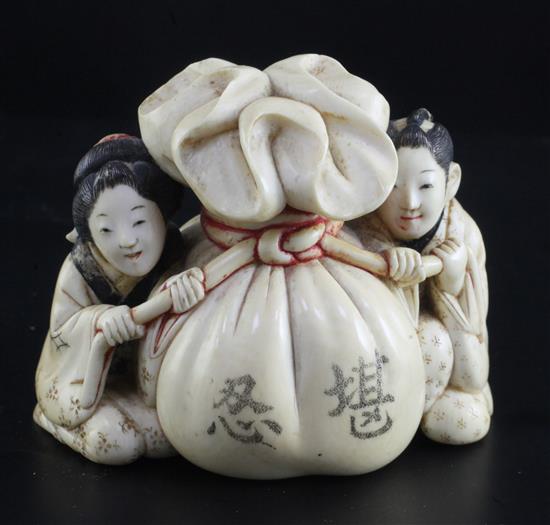 A Japanese ivory okimono of a man and woman holding the cords of a tied sack between them, Meiji period, width 7.3cm